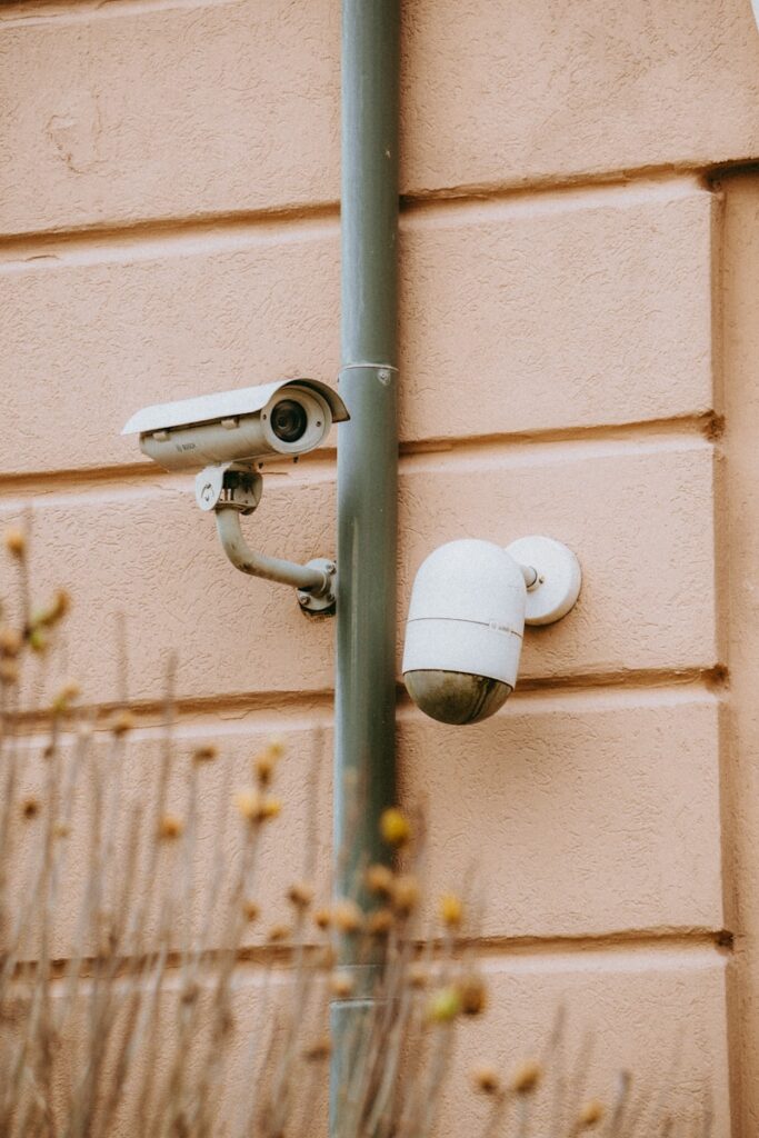 two cameras attached to a metal pole near a building