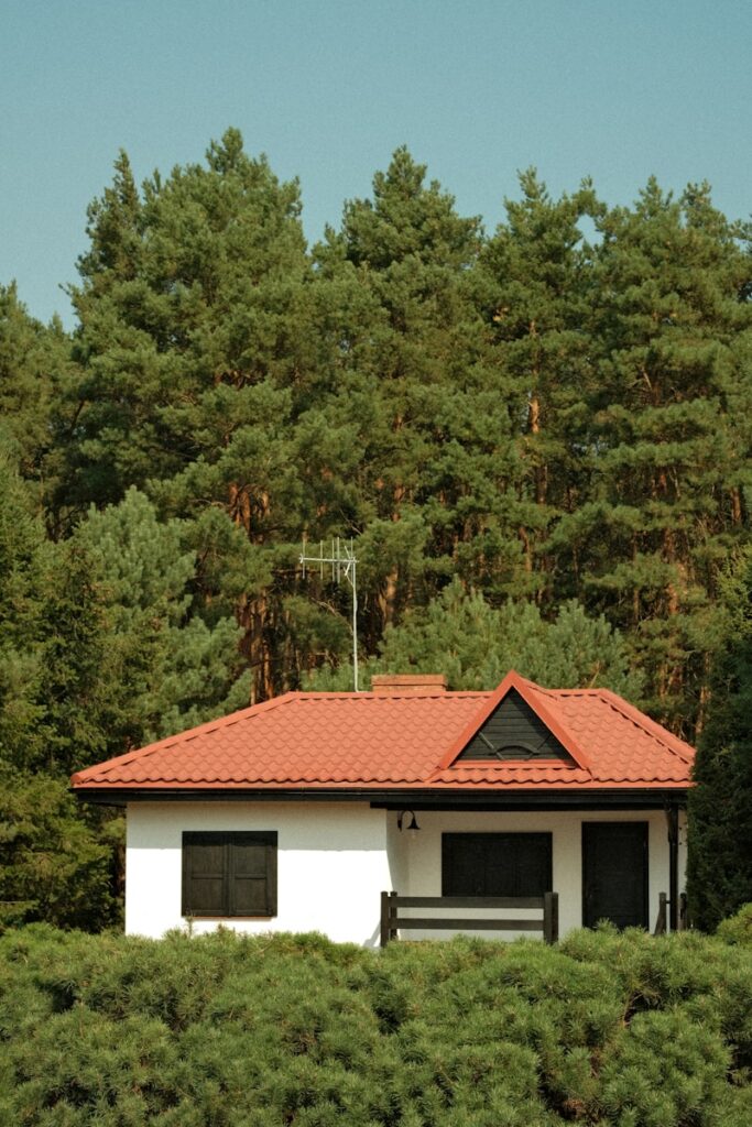 A white house with a red roof surrounded by trees